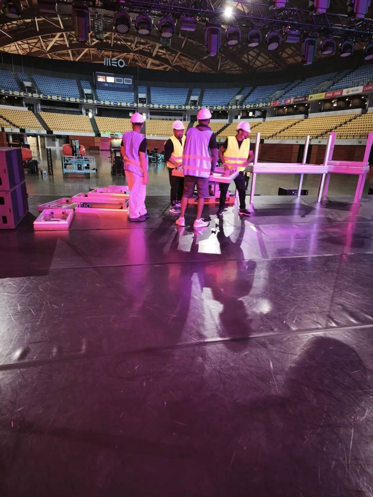 Equipa de stagehands com coletes reflectores em montagem de palco.
